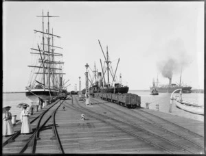 Timaru, showing wharves with ship Pleione alongside; filled railway carts and women holding umbrellas