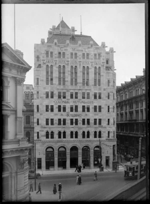 The Colonial Mutual Life building, corner of Willis Street and Lambton Quay, Wellington, featuring people walking in the street, a tram and a motor car