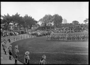 An outdoor ceremony [reception for the Prince of Wales?] in Whanganui, showing uniformed cadets standing in centre and at perimetre of a velodrome, in front of a crowd