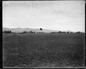 Monoplane Southern Cross aircraft flying low over unidentified field