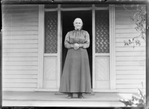 A woman [Mrs Rosindale?] standing on verandah of a house, location unidentified
