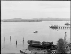 Tauranga Harbour, Bay of Plenty, with a steam boat, a yacht docked at the pier, a small anchored in the harbour and a boat in dry dock in the foreground
