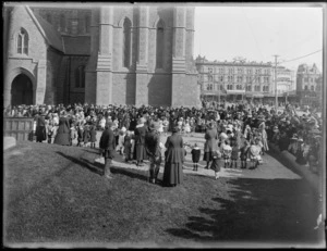 Crowds of people gather in front of the Cathedral Church, Cathedral Square, Christchurch