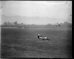 Biplane aircraft on a field at an unidentified location, including trees and hills in the background