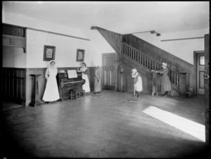 Housemaids dusting and sweeping in a foyer of a large house