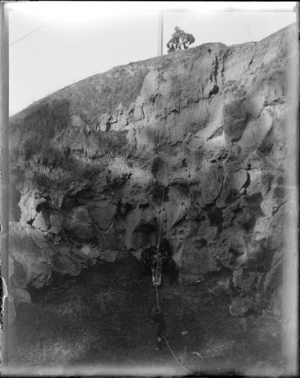 Group of boy scouts in training hoisting a stretcher down a steep rock