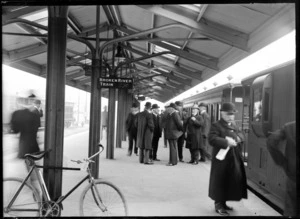Christchurch Railway Station, with passengers waiting on the platform alongside a train and a bicycle in the foreground