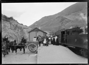 Arthur's Pass Railway Station, featuring a steam train, passengers on the platform and horses and carts with the passengers and their luggage