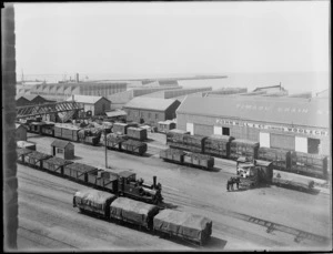 John Mill and Company Ltd Wool and Grain Store, Timaru, with a steam train, freight carriages, horse and cart in the foreground
