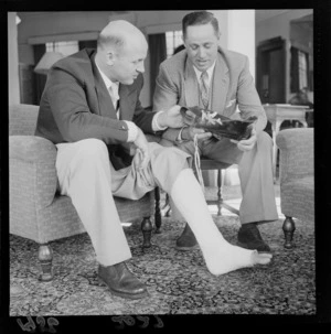 C J van Wyk (left), Springbok rugby union football player on the 1956 tour, looking at a football boot with South African Mr M J Wessels