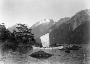 Small sailing ship on the Hollyford River, Southland, with snow capped mountains behind