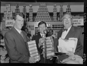Unidentified man, with Sir Edmund Hillary and Selwyn Toogood, with give aways products of Rinso at the opening week of the Self Help store, Wellington