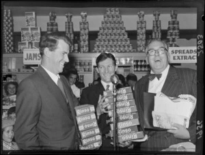Unidentified man, with celebrities Sir Edmund Hillary and Selwyn Toogood, with give away products of Rinso at the opening week of the Self Help store, Lambton Quay, Wellington