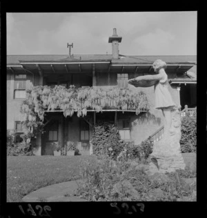 Garden statue in front of house, with Wisteria vine growing on the veranda, private family residence, unknown location