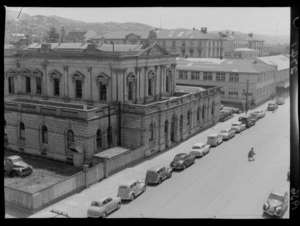 Parked cars lining the streets outside of the Supreme Court, Wellington, with Old Government Buildings in background