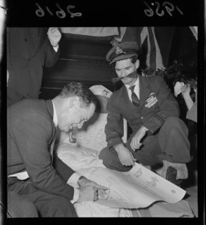 Double-amputee and World War II veteran Douglas Robert Steuart Bader signing a declaration while Norm Robson, who is dressed as Hitler, looks on