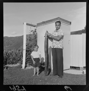 Mr H Reid holding a 25 pounds fresh water eel and an unidentified child next to him