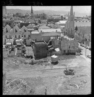 Site being cleared for construction in Willis Street, Wellington, including view of a cottages on Ghuznee Street, cigarette advertising, and St Peter's Anglican Church