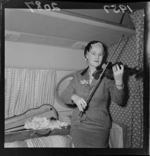 Lady McKee playing her violin in the cabin of the Royal Air Force Comet airliner