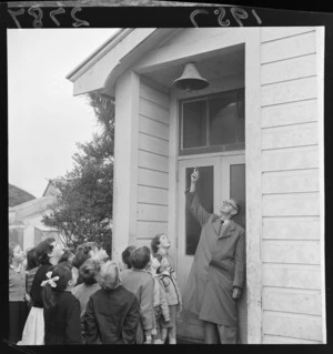 The principal, Mr anderson, showing the 100 year old Wainuiomata School bell to children, Lower Hutt, Wellington Region