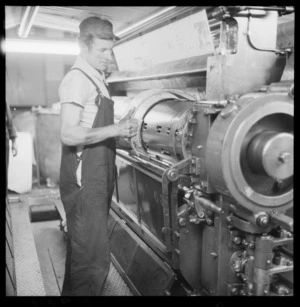 An unidentified man attaching a curved stereotype plate to the cylinder of a rotary printing press at The Evening Post newspaper printing works, Willis St, Wellington
