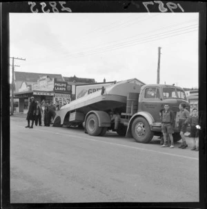 A petrol tanker belonging to Europa Oil New Zealand Ltd, which has foundered on Johnsonville Road, surrounded by interested bystanders, and attended by a [motorcycle?] traffic officer