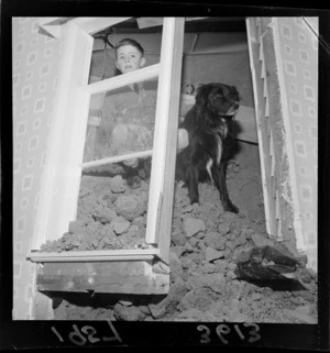 Boy and dog viewing interior of house affected by landslip, Vogeltown, Wellington