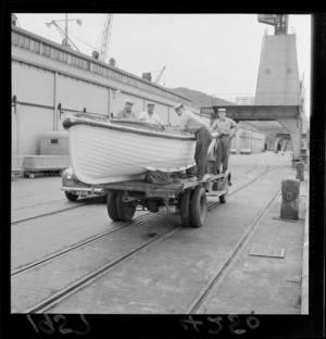 Unidentified sailors on the back of a truck with a boat from Royal New Zealand Navy survey ship Lachlan, at Wellington wharves