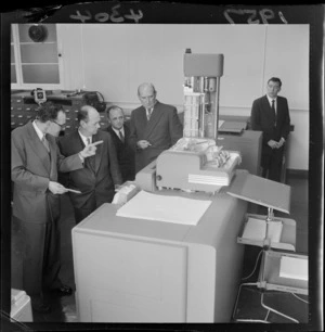 Mr Watts with a group of unidentified men inspecting a sorting machine, at the New Zealand Treasury, Wellington