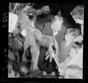 Children attaching a Christmas present to the Christmas tree