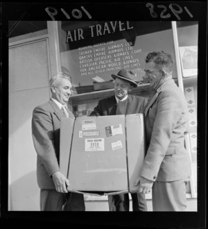 Three unidentified men holding a carton of Polio Vaccine, standing outside the Tasman Empire Airways Ltd office