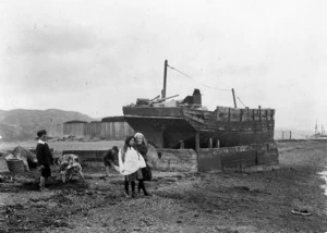 Children playing next to the wreck of the ship 'Maori', in Pipitea Street, Wellington