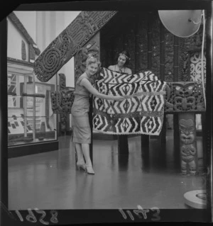 Miss United States (Miss Charlotte Sheffield) at the Dominion Museum, Wellington, with a feathered cloak and pataka