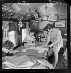 Circus workers sewing costumes in their railway carriage accommodation