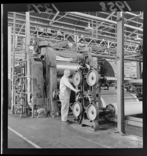 Interior of Dunlop rubber factory, Upper Hutt, showing unidentified man using larger rollers