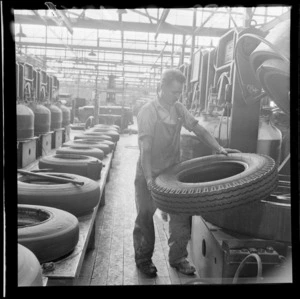 Interior of dunlop rubber factory, Upper Hutt, showing unidentified man pressing tyres in machine