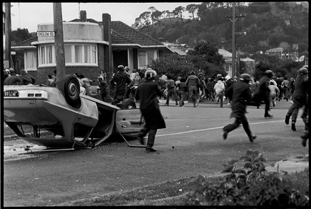 The anti-Tour protest group retreats from the Red Squad baton charge as it passes the overturned unmarked police car and arrives at Dominion Rd