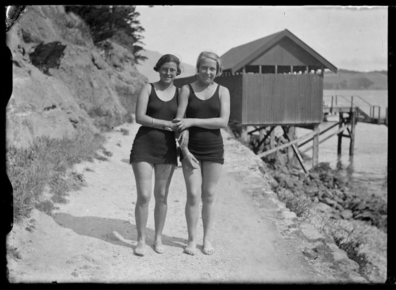Two young women wearing swimwear, one appears to be wearing a belt over her swimwear.