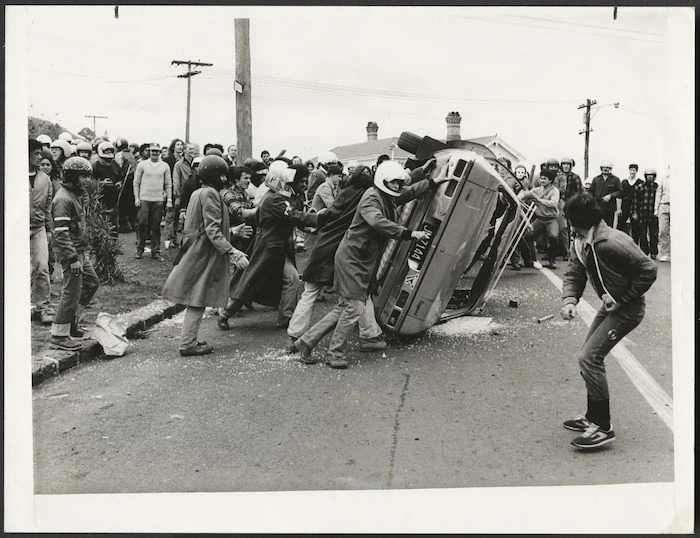 Anti Springbok tour demonstrators overturn a car, Auckland, New Zealand - Photograph taken by an Auckland Star photographer
