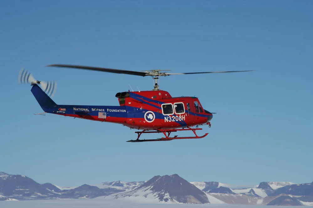NSF helicopter in the air with mountains in the background
