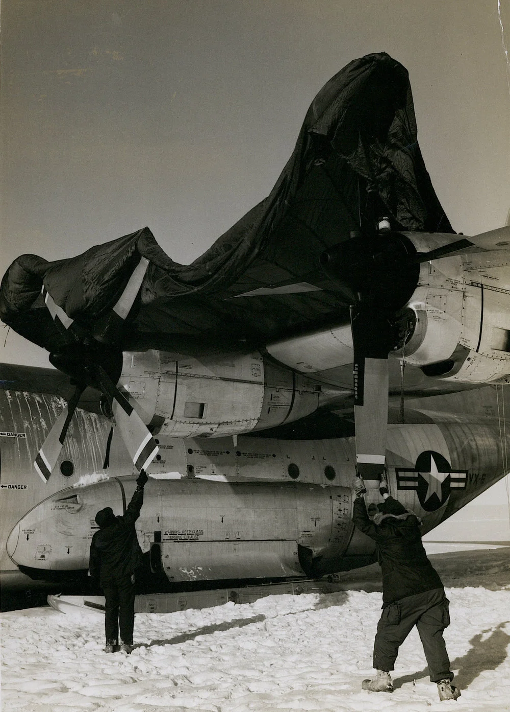 Crew members of C-130 Hercules transport downed in Antarctica's interior with engine trouble cover the plane's engines with a parachute