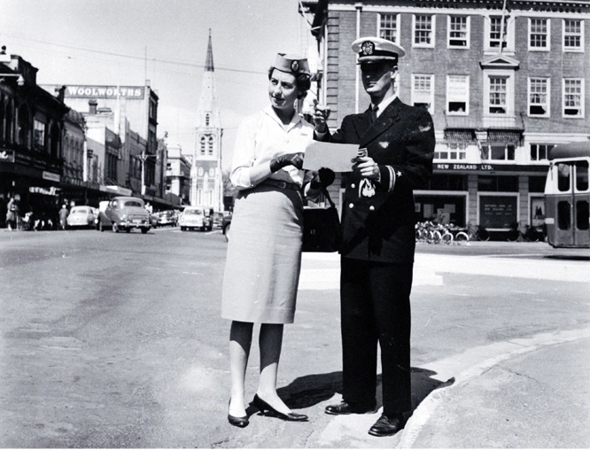 Male and female cabin crew of TEAL standing at the corner of Colombo and Armagh Streets