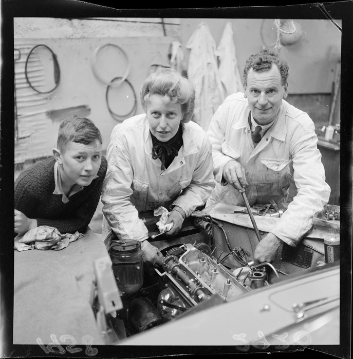 Mechanic, Sybil Lupp, with husband Lionel Archer and unidentified boy, checking over an engine
