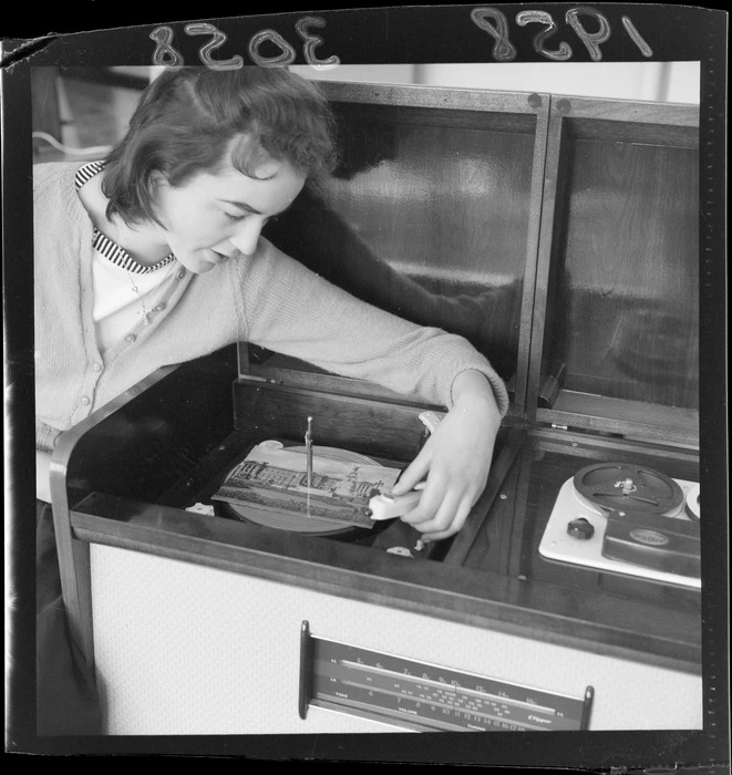 Unidentified woman placing a greeting card on a turntable to demonstrate that it can also be used as a record