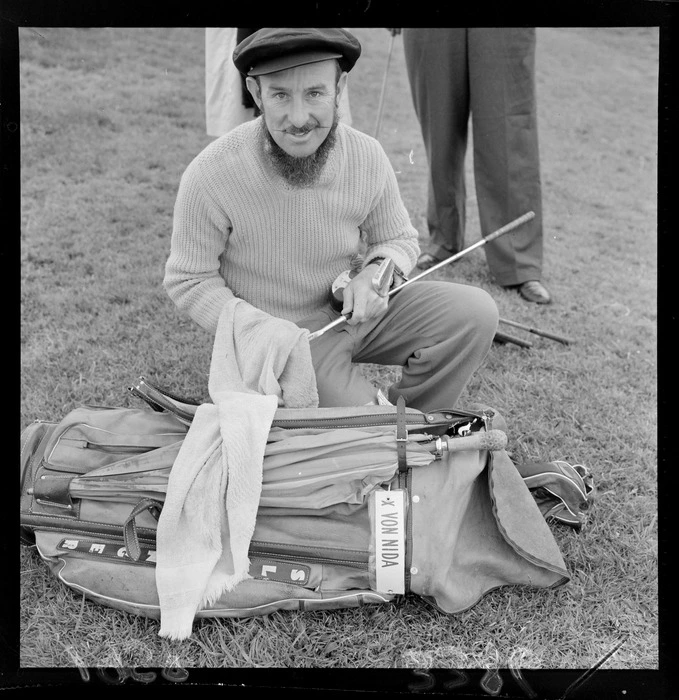 Unidentified man [X Von Nida?] polishing his golf clubs, Paraparaumu Golf Club, Kapiti Coast District, Wellington Region, including golf bag and waxed moustache