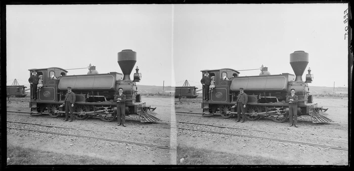 Steam locomotive at railway yards, including unidentified railways workers and a small girl seated in train cab, Dunedin area, Otago Region