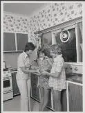 Jennifer Turrall, 13 and Sally Lockyer, 14 members of the Australian swimming team in the Commonwealth Games in New Zealand in January 1974, in the kitchen with Mrs Turrall [picture].