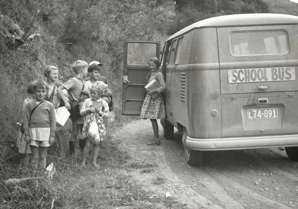School children alongside a Volkswagen Kombi school bus on a country road