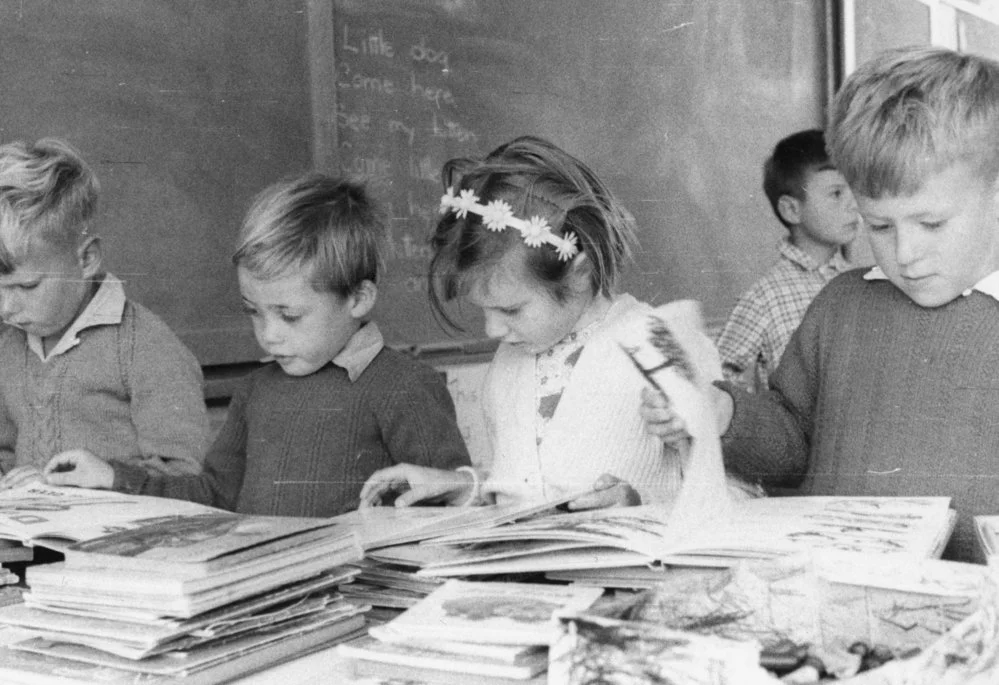 School children in classroom looking at books