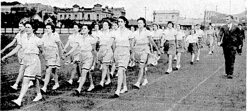 Eyeulng Post" Photo. Girls at the Basin Reserve this morning practising for the inter-house marching contest lo be held on Wednesday evening. They are being trained by Mr. C. McCalman (right), physical ivelfare officer of the Department of Internal Affairs. (Evening Post, 25 February 1941)